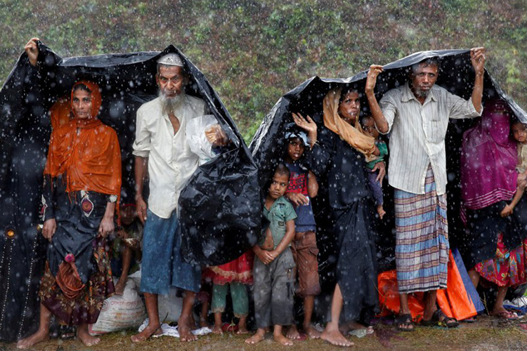 Para pengungsi rohingya berlindung dari hujan di sebuah kamp di Cox’s Bazar, Bangladesh, pada tanggal 17 September 2017